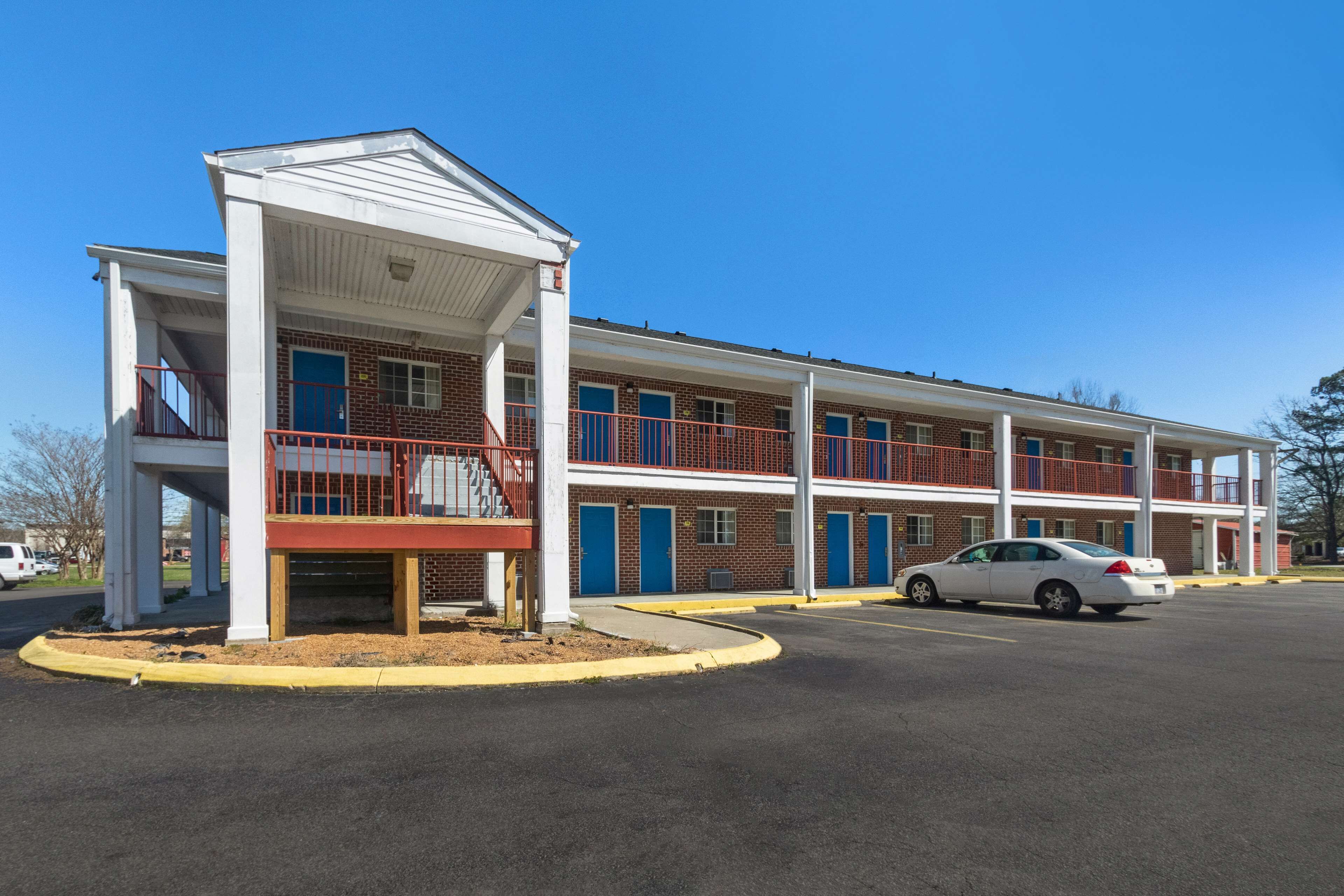 A two-story motel with a covered front porch and a parking lot.