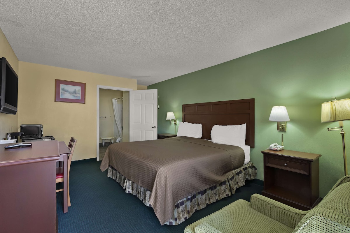 A hotel room with a bed, bedside lamps, a desk with a computer, and a chair.