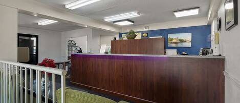 A reception area with a wooden counter, a blue accent wall, and a framed picture.