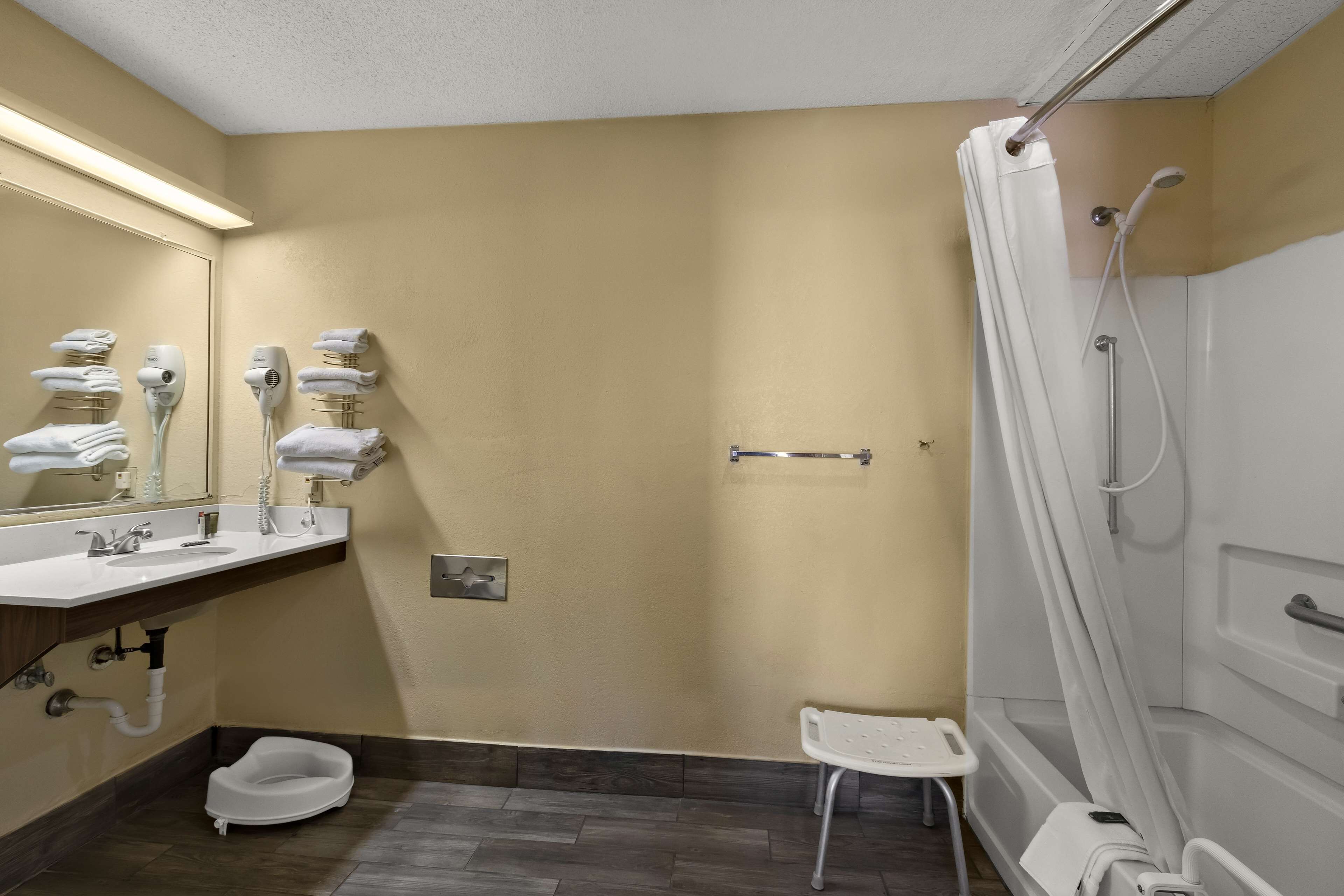 Un baño con ducha, lavabo con espejo y retrete.