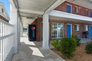 A building with a Pepsi vending machine, a covered walkway, and a brick facade.