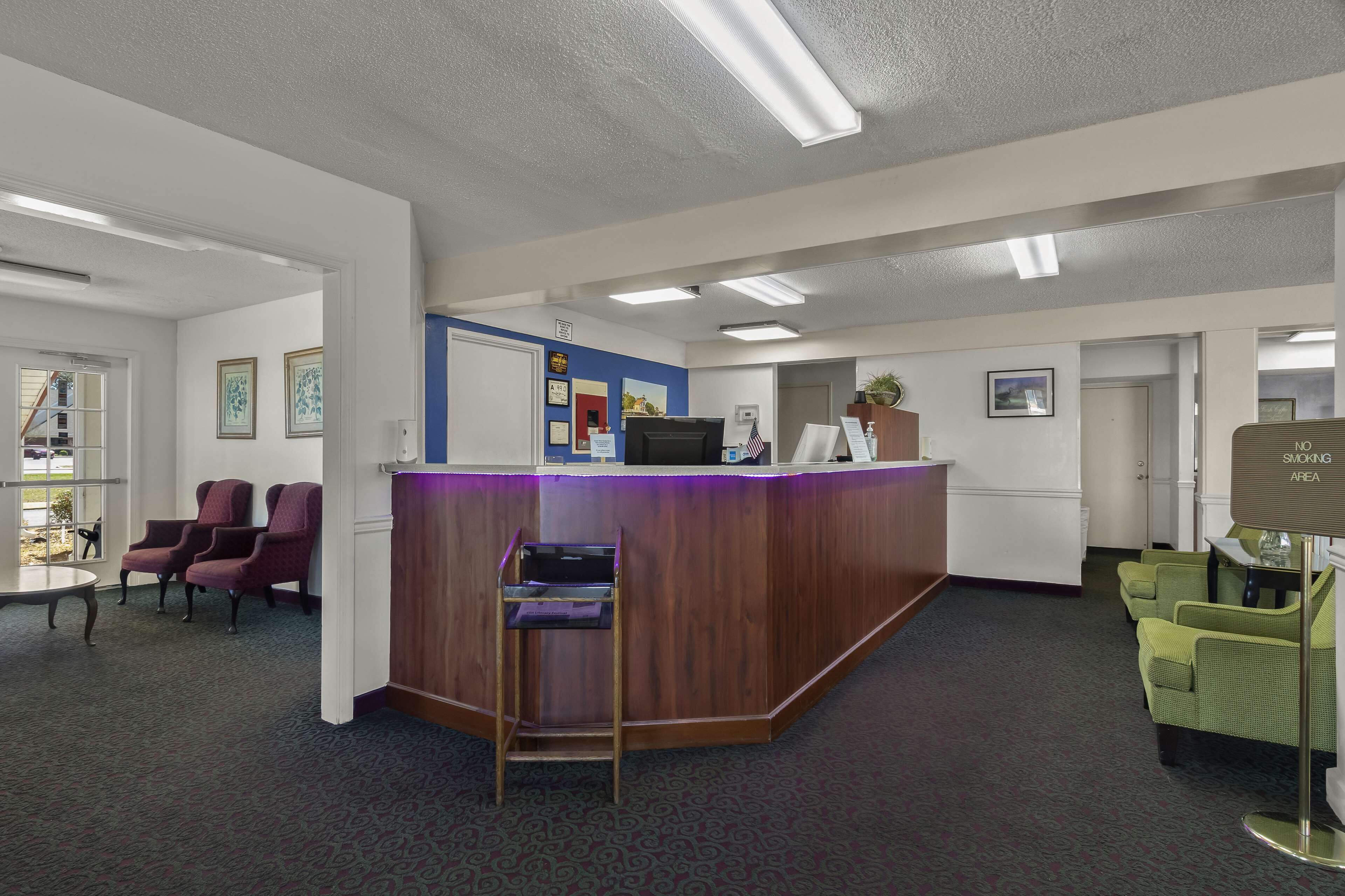 A reception area with a wooden counter, purple and green chairs, and a blue accent wall.