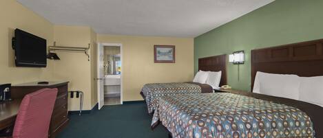 Ein Hotelzimmer mit zwei Betten, einem Schreibtisch mit Stuhl, einem Fernseher und einer Badezimmertür.