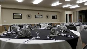 A conference room with round tables, each set with cutlery, glasses, and napkins.