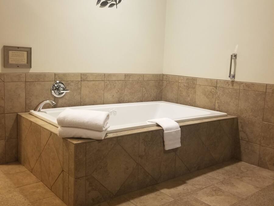 Un baño con una bañera independiente, un perchero de pared y una placa enmarcada en la pared.
