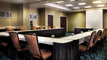 Un salón de conferencias con una larga mesa, sillas y una pantalla para proyector.