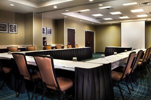 Un salón de conferencias con una larga mesa, sillas y una pantalla para proyector.