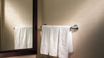 A bathroom with a granite countertop sink, a mirror, and two white towels hanging on towel hooks.