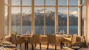 A dining area with a table set for two, overlooking a lake and mountains. - Rosewood Matakauri (Closeburn)