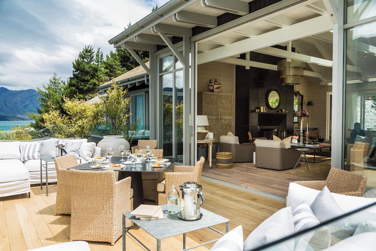 A spacious outdoor living area with a dining table, wicker furniture, and a view of the mountains.