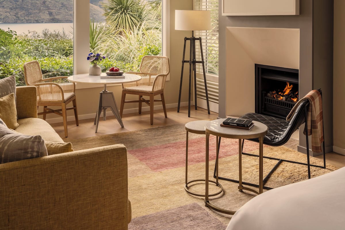 A cozy room with a fireplace, a dining area with chairs, a sofa, and a view of mountains through large windows.