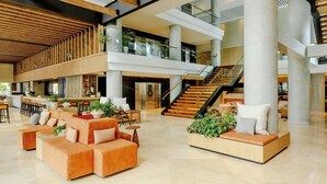 A spacious lobby with a modern design, featuring a central seating area with sofas and a coffee table, surrounded by a high ceiling with wooden beams and a staircase leading to an upper level. - Sheraton Asuncion Hotel (Asuncion)