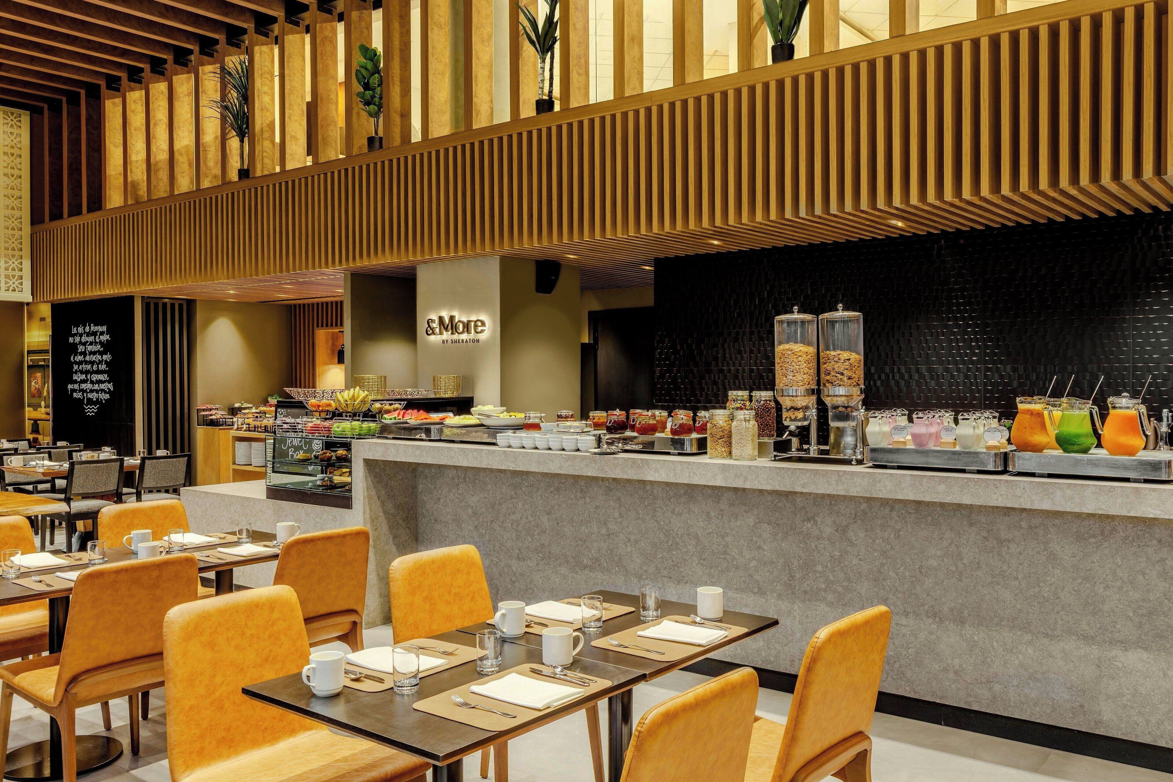 Un restaurante moderno con una barra central, zona de asientos y una pared negra con textura.