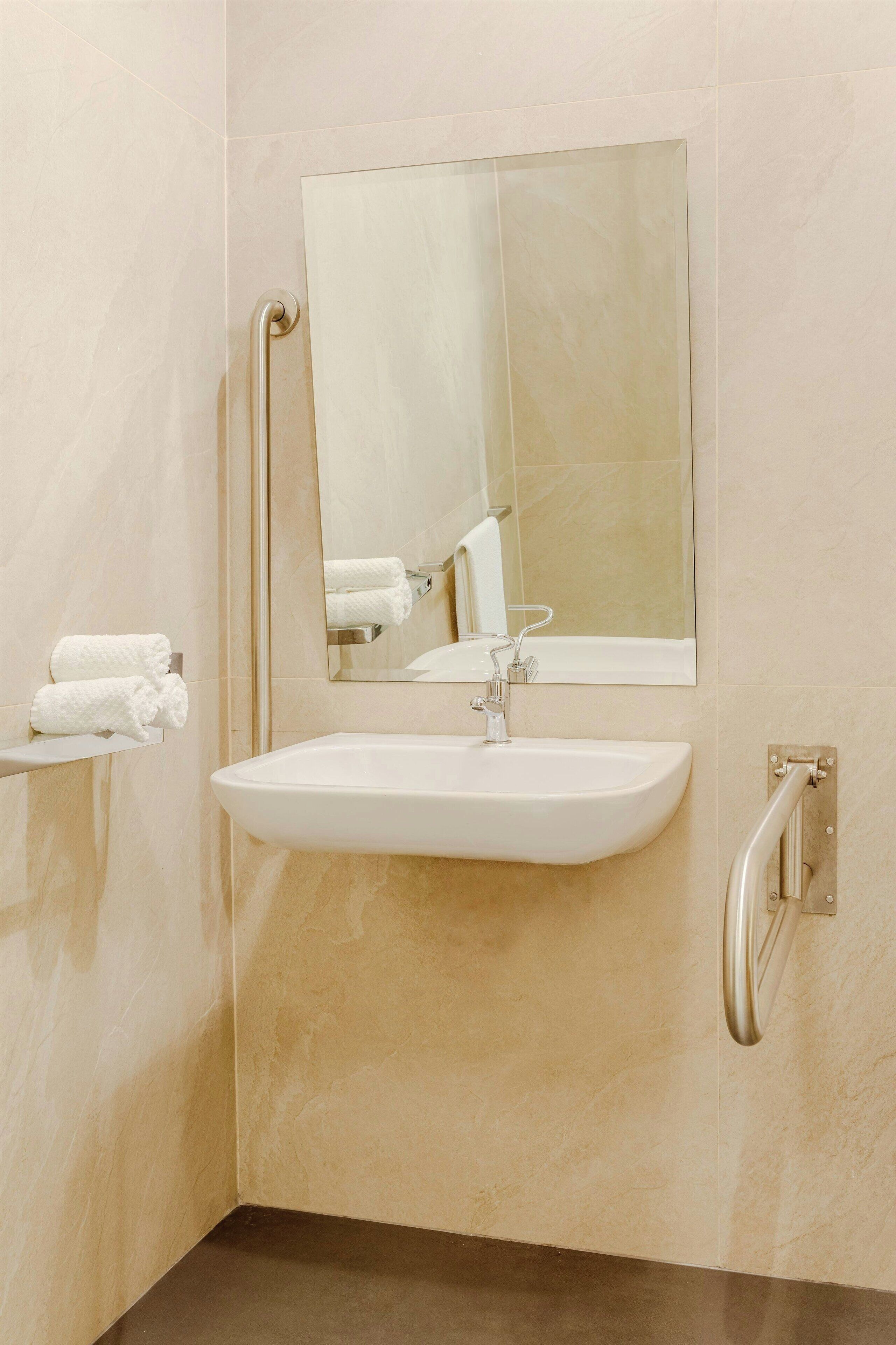 A bathroom with a white sink, a mirror, and a towel rack.