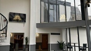 A spacious interior with a high ceiling, a chandelier, black leather sofas, and a staircase. - Britannia Hotel Wigan (Wigan)