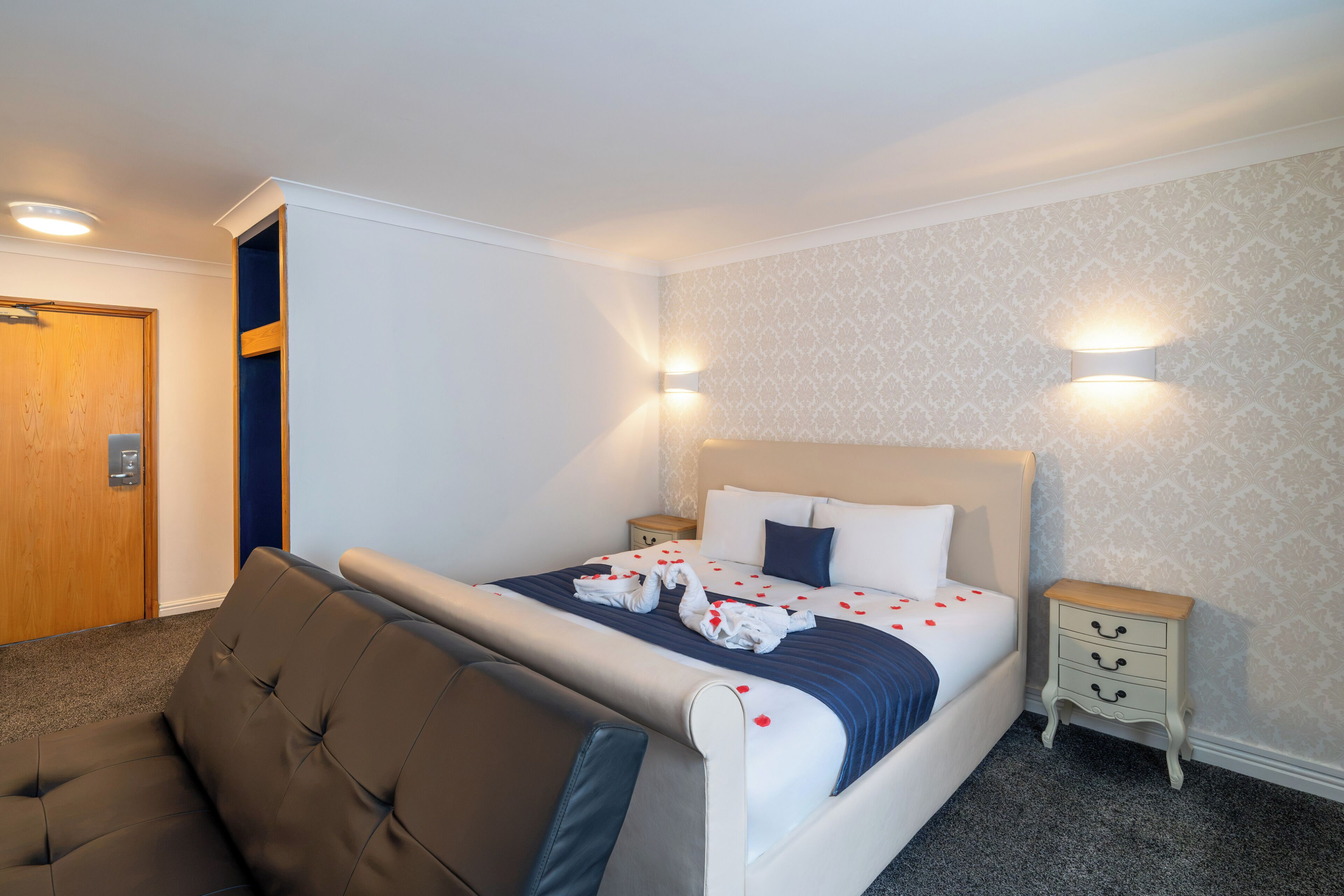Una camera d'albergo con un letto, una zona salotto e una porta.