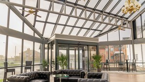 A spacious indoor area with a glass ceiling, leather sofas, a small table, and potted plants. - Britannia Hotel Wigan (Wigan)