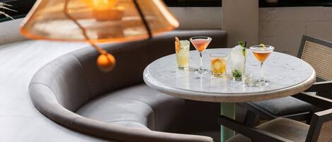A round table with drinks and a hanging light fixture.