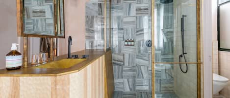 A modern bathroom with a curved vanity, a glass shower enclosure, and a marble-patterned wall.