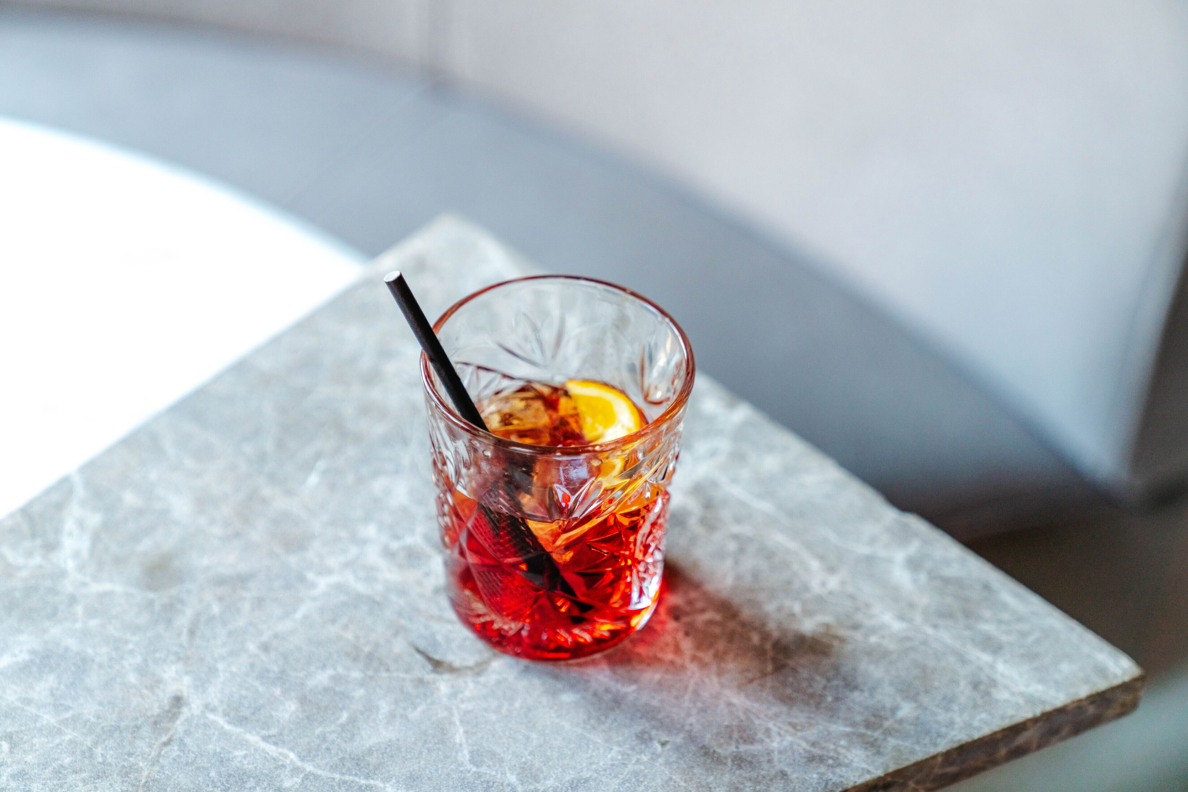 A glass with a straw and a lemon slice on a marble surface.