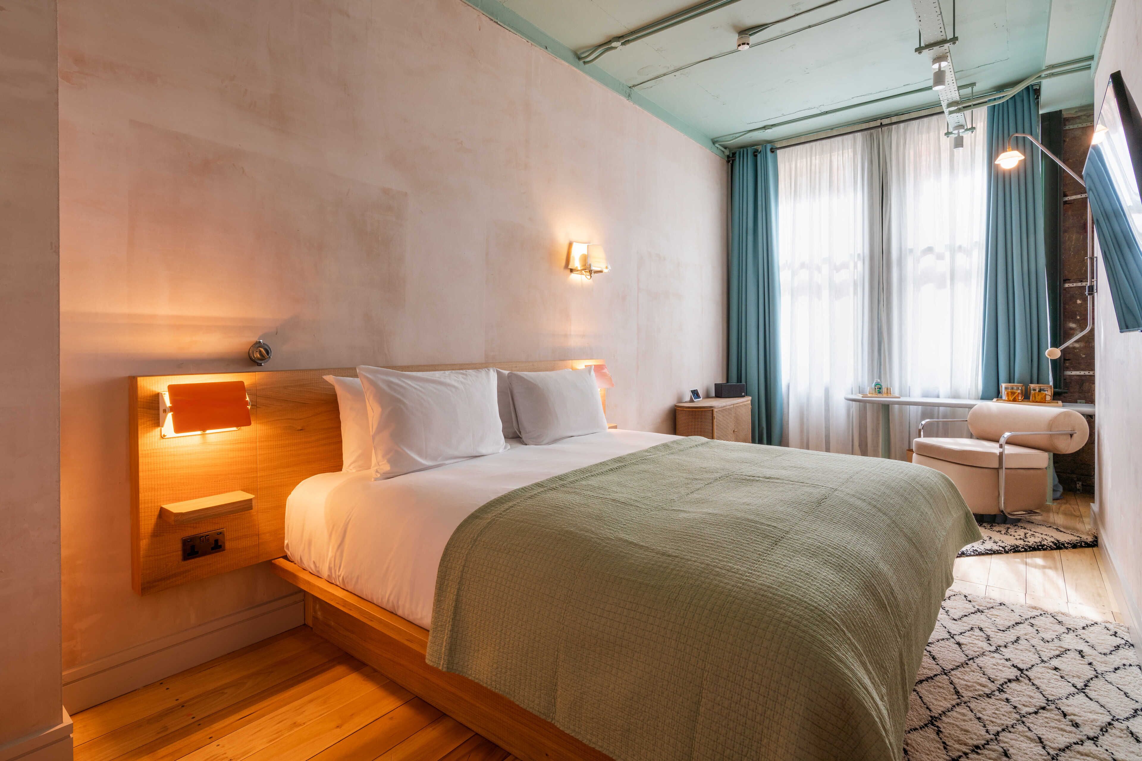 A modern hotel room with a large bed, bedside tables, a desk, and a chair.