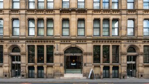A large, historic building with a symmetrical facade, large windows, and a central entrance with a glass door.