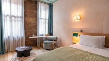 Une chambre d’hôtel avec un lit, une chaise, une petite table et une fenêtre avec des rideaux.