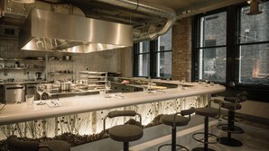 A modern kitchen with a central island, bar stools, and large windows.