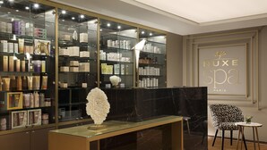 A modern spa reception area with a glass display of spa products, a marble reception desk, and a stylish chair. - Hôtel Barrière Le Westminster Le Touquet (Le Touquet-Paris-Plage)