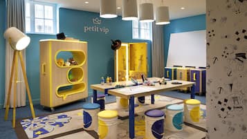 Children can play and learn in this vibrant playroom with a wooden playhouse, desk, and educational materials.