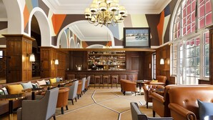 A bar area with a bar counter, stools, and a well-stocked liquor shelf. - Hôtel Barrière Le Westminster Le Touquet (Le Touquet-Paris-Plage)