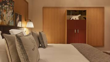 A hotel room with a large bed, a wardrobe, a nightstand with a lamp, and a painting on the wall.