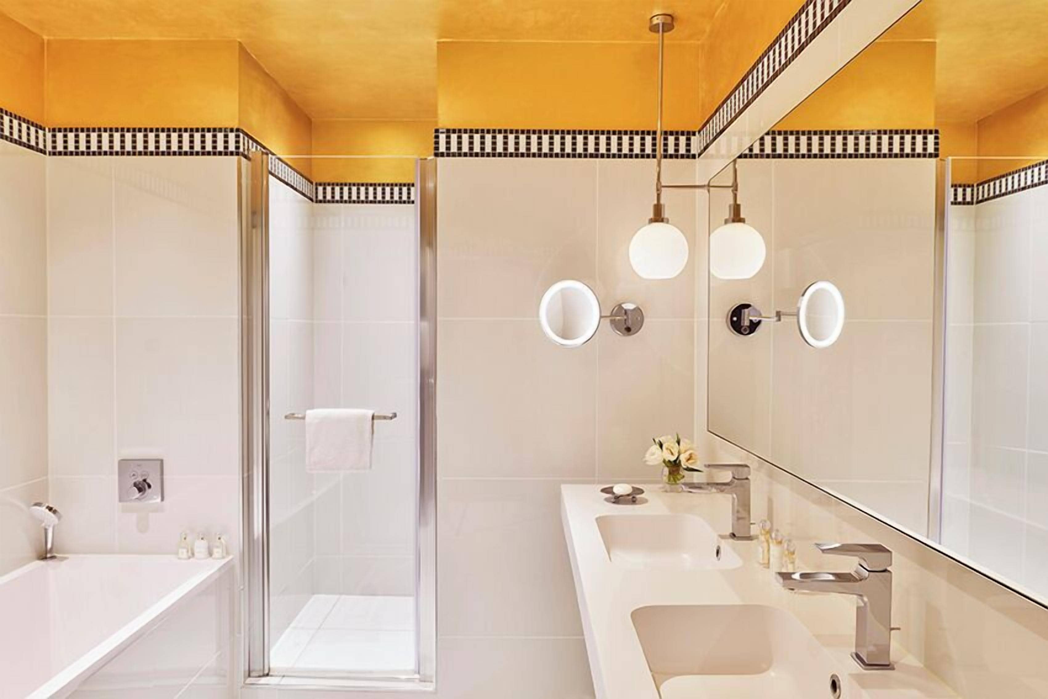 A modern bathroom with a glass shower enclosure, a large mirror, and a vanity with a sink and mirror.