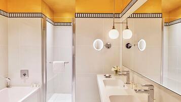 A modern bathroom with a glass shower enclosure, a large mirror, and a vanity with a sink and mirror.