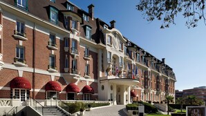 A multi-story hotel with a grand entrance, red awnings, and a well-maintained garden. - Hôtel Barrière Le Westminster Le Touquet (Le Touquet-Paris-Plage)