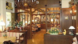 A cozy, well-lit room with wooden furniture, a large chandelier, and a ship's wheel decoration. - Nordseehotel Freese (Juist)