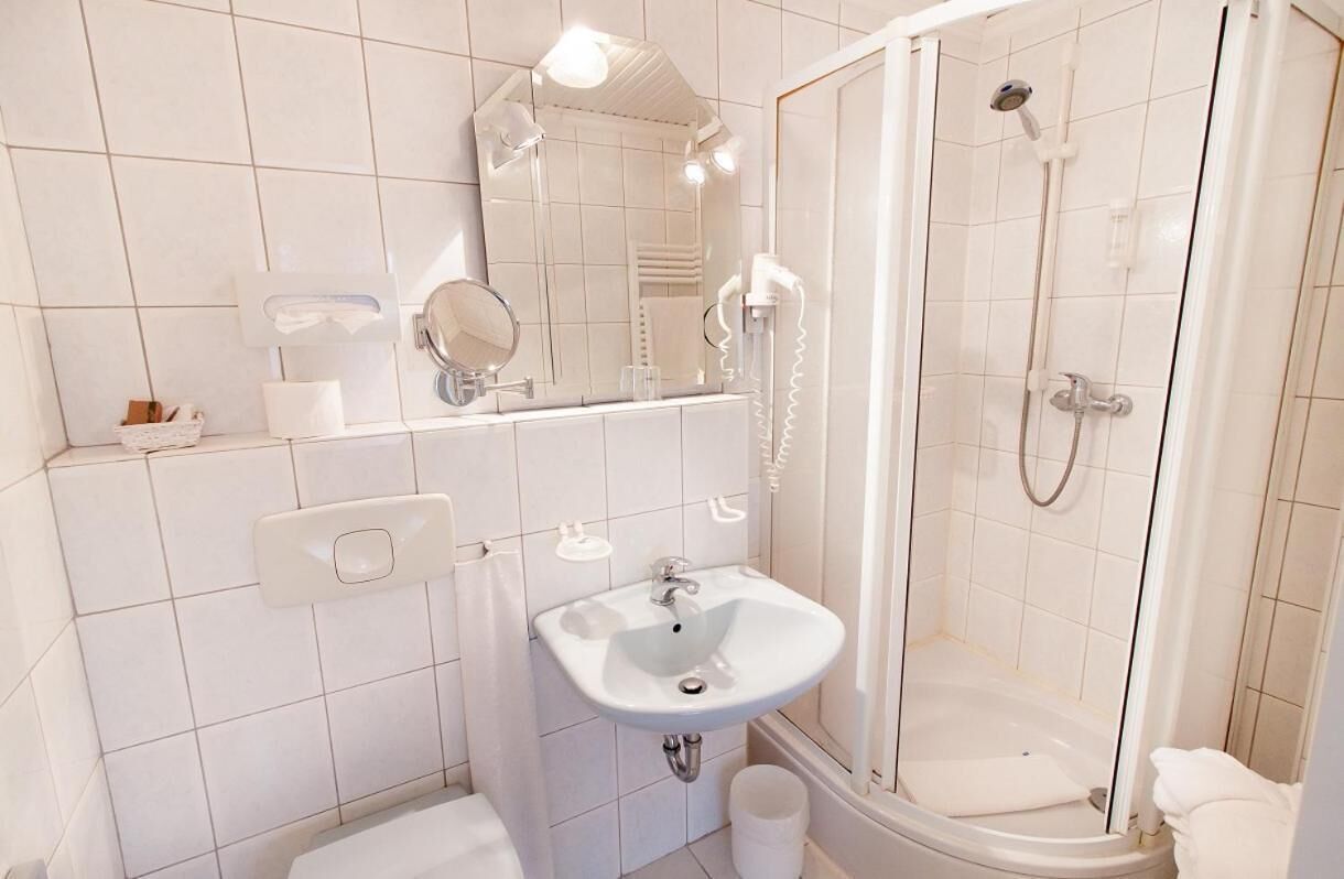 A modern bathroom with a white sink, mirror, and shower.