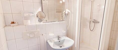 A modern bathroom with a white sink, mirror, and shower.