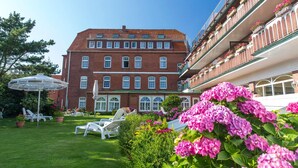 A large brick building with multiple balconies, a well-maintained lawn, and outdoor seating areas. - Nordseehotel Freese (Juist)