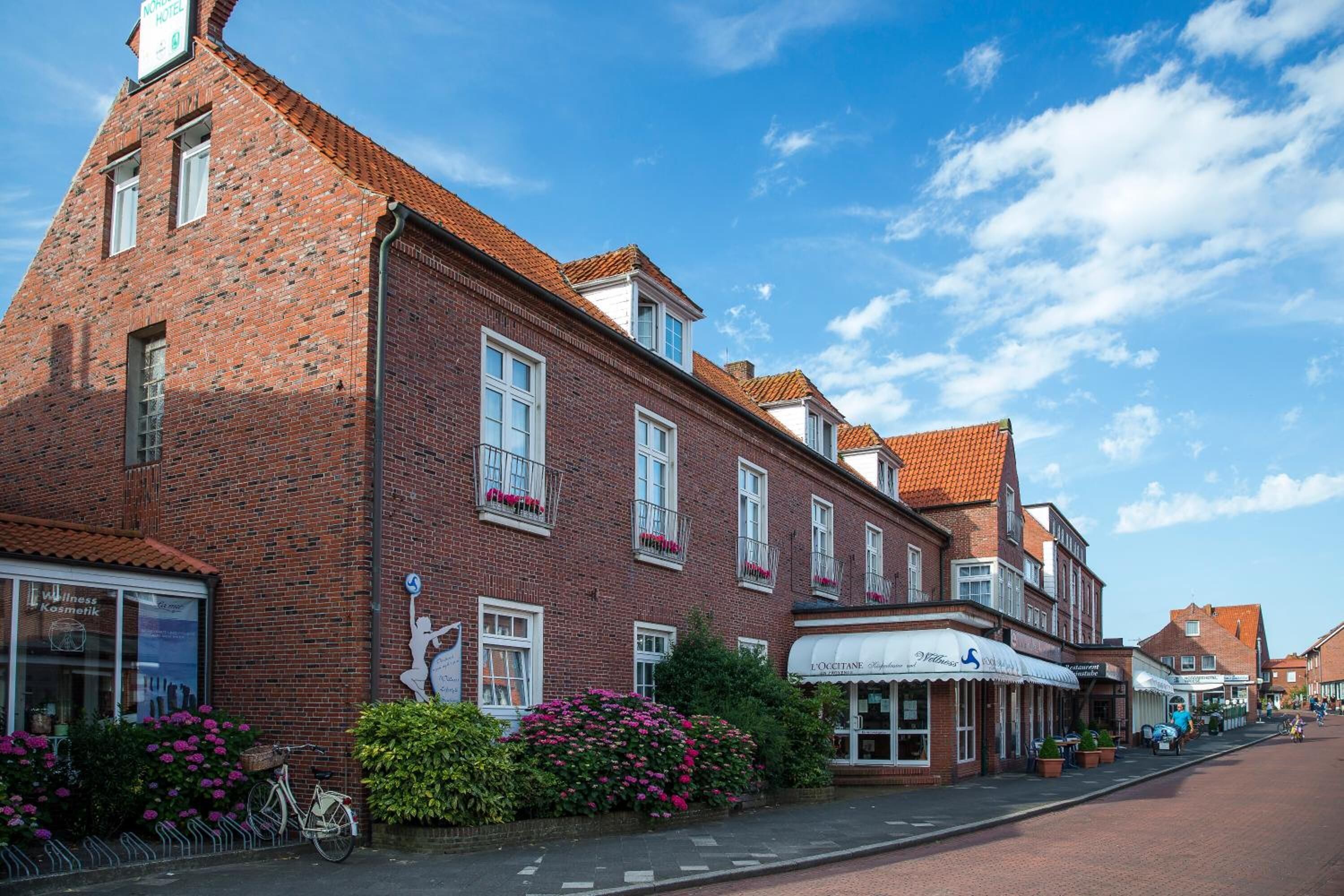 A red brick building with a traditional European architectural style, featuring multiple windows and a visible storefront with a sign.