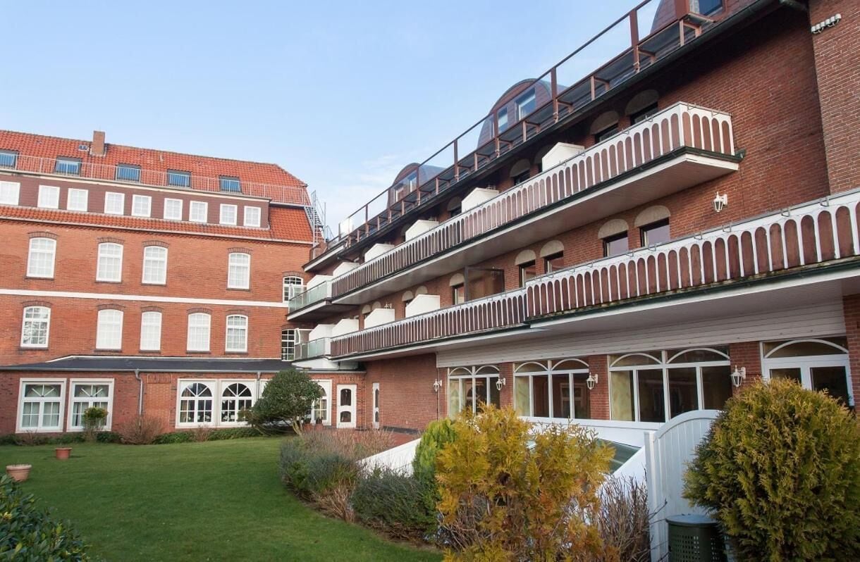 Ein mehrstöckiges Gebäude mit Ziegelbauweise, großen Fenstern und einem Balkon mit Glasgeländer.