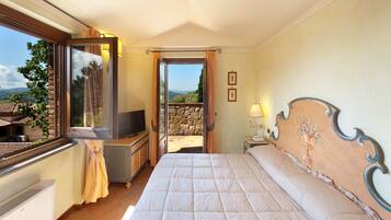 A hotel room with a bed, a TV, a desk, and a view of the outdoors.