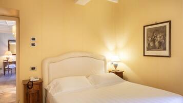 Ein Hotelzimmer mit einem Bett, einem Nachttisch mit Lampe, einem Telefon und einem gerahmten Bild an der Wand.