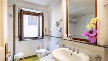 Un bagno con il water, un bidet, un lavandino e una finestra.
