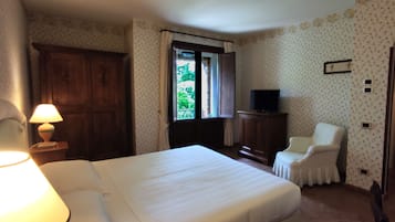 A hotel room with a bed, a chair, a TV, and a wardrobe.