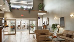 Eine geräumige Lobby mit einer Rezeption, zwei Sofas, einem Couchtisch und einem großen Fenster, das für natürliches Licht sorgt.
