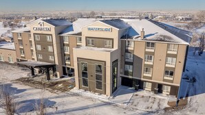 Ein mehrstöckiges Hotel mit den Schildern "CANALTAI" und "WATERSLIDE", das ein modernes architektonisches Design mit großen Fenstern und einem Flachdach aufweist.