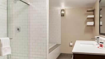 Un baño moderno con cabina de ducha de vidrio, un lavamanos blanco y una pared color beige.
