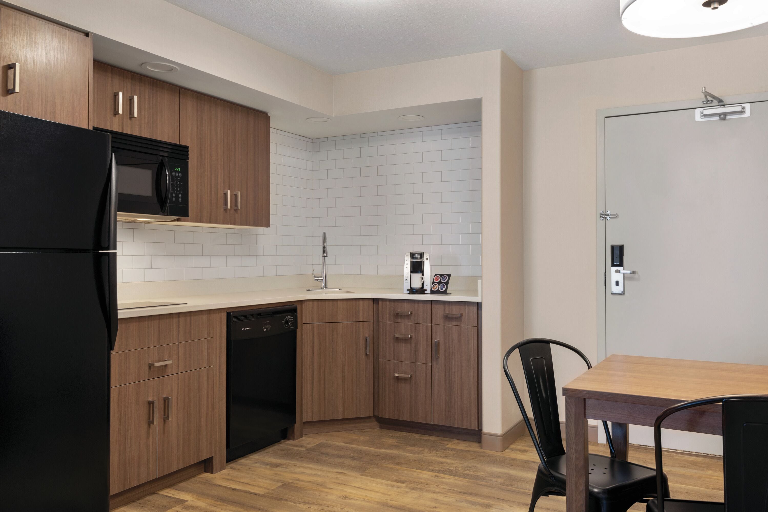 Una cocina moderna con armarios de madera, un refrigerador negro, un microondas y una cafetera.