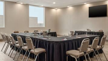 A conference room with a long table, chairs, and a flat-screen TV on the wall.